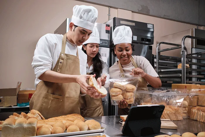 Three young bakery founders live-streaming pastry sales online from their kitchen.